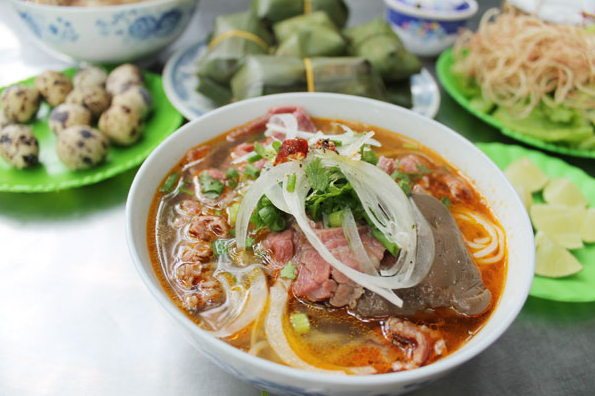 Tô bún bò Huế bốc khói nghi ngút, đầy đủ rau sống.