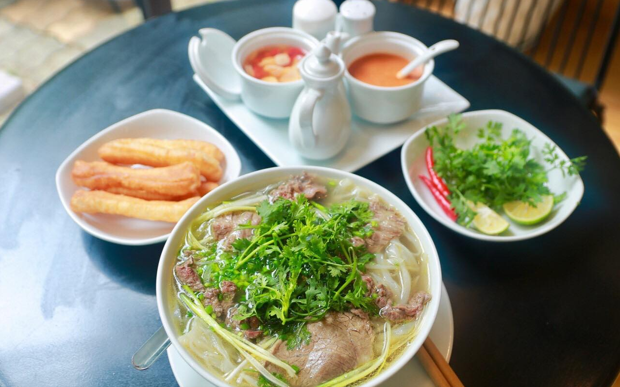 Bát phở bò nóng hổi, khói bốc lên nghi ngút trên bàn ăn vỉa hè.