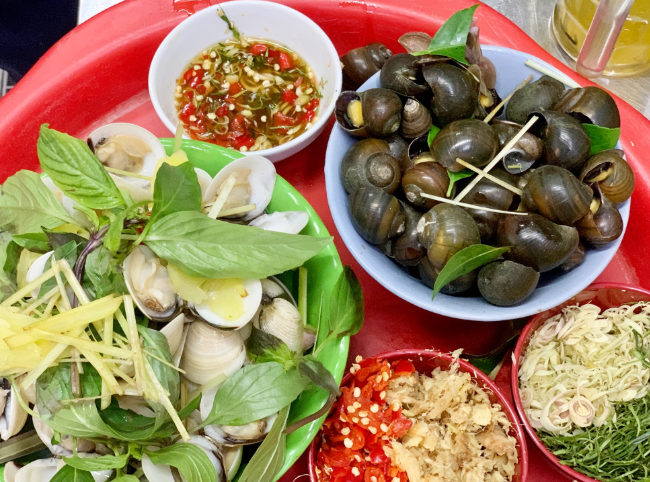 Bàn ăn vỉa hè với đĩa ốc luộc, bát nước chấm sả ớt hấp dẫn.