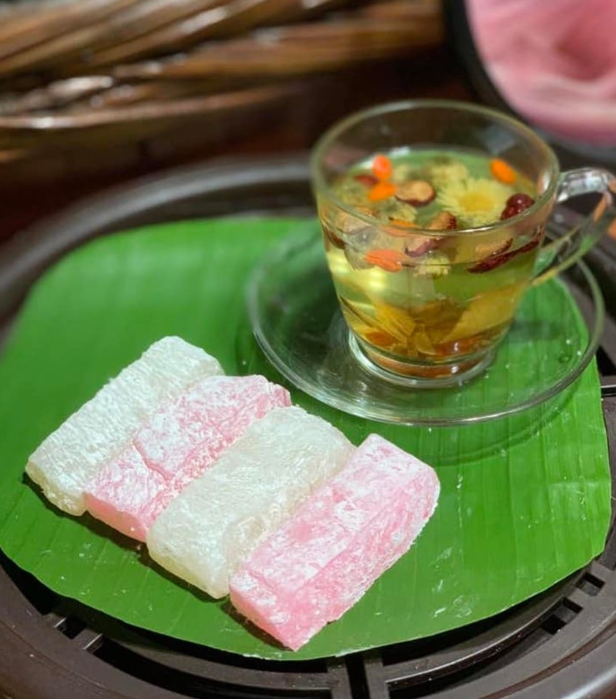 Khay bánh hồng Quy Nhơn màu hồng nhạt, được cắt thành miếng vuông, xếp gọn gàng trên lá chuối.