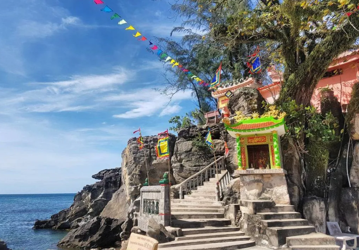 Con đường đá dẫn lên Dinh Cậu Phú Quốc, hai bên là sóng biển dập dờn và hoàng hôn rực rỡ phía xa.