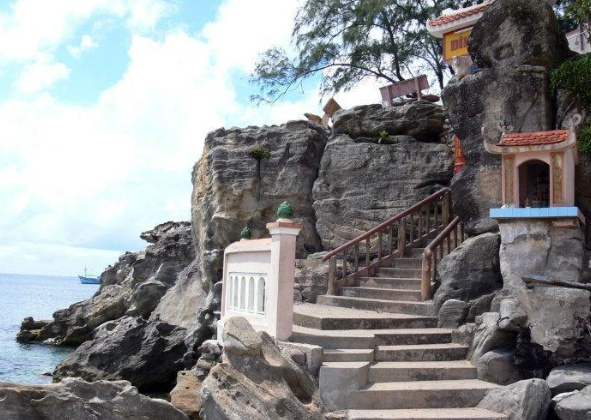 Bậc thang đá dẫn lên Dinh Cậu Phú Quốc, bao quanh là rặng dừa xanh và biển trong vắt.