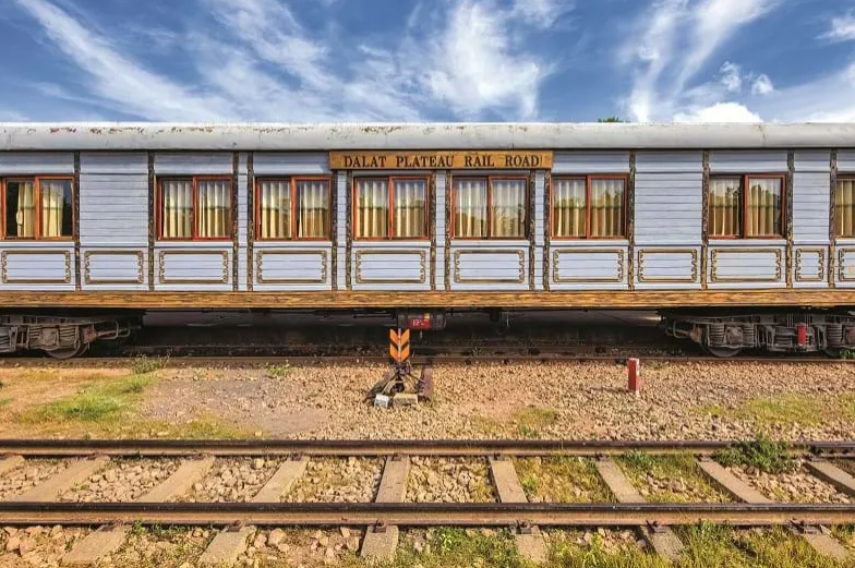  Toa tàu cổ màu nâu gỗ chạy từ ga Đà Lạt đến Trại Mát giữa cảnh núi rừng sương phủ.