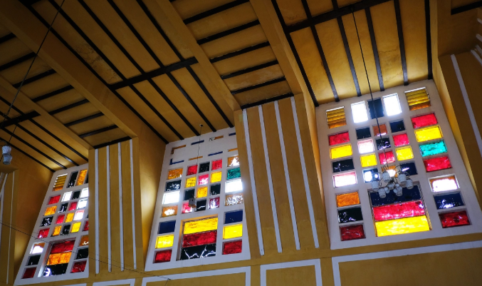 Nắng chiều chiếu qua khung cửa kính màu bên trong ga Đà Lạt, tạo nên không gian ấm áp.