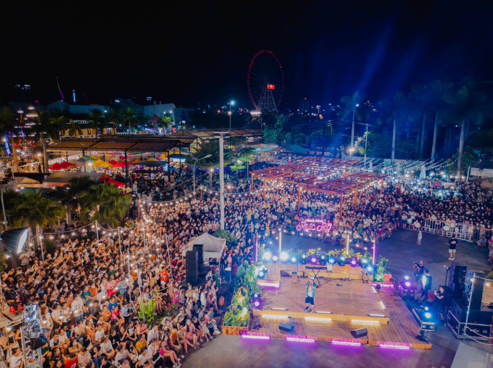Sân khấu ngoài trời tại Helio Đà Nẵng, ánh đèn sân khấu rực rỡ, đông khán giả cổ vũ.