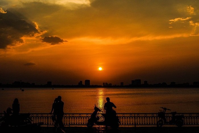 Đường phố phản chiếu ánh hoàng hôn, người qua lại chậm rãi, yên bình.