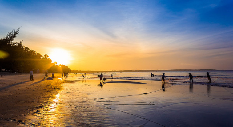 Cảnh bình minh ở Mũi Né, ánh nắng rực rỡ phủ khắp mặt nước và bãi cát.
