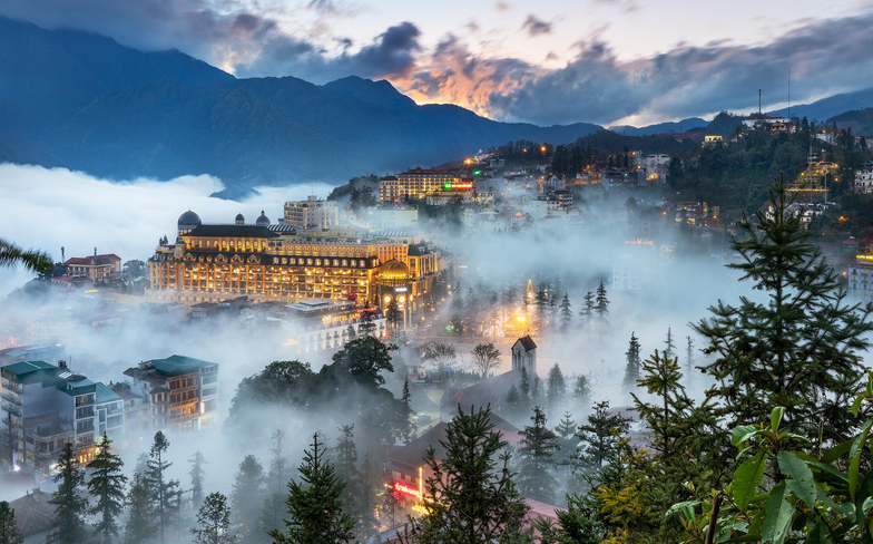 Phong cảnh Sapa hoặc Mẫu Sơn mờ sương, vài mái nhà ẩn hiện trong làn khói lạnh.