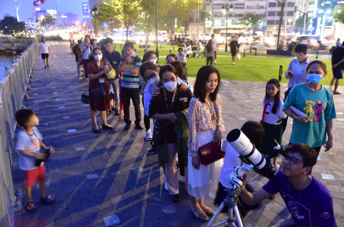 Người dân sử dụng kính thiên văn nhỏ để quan sát nguyệt thực ngoài trời.