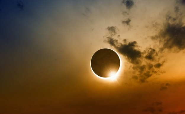 Hình ảnh Mặt Trăng đang che khuất một phần Mặt Trời, tạo nên ánh viền sáng kỳ ảo giữa bầu trời đen.