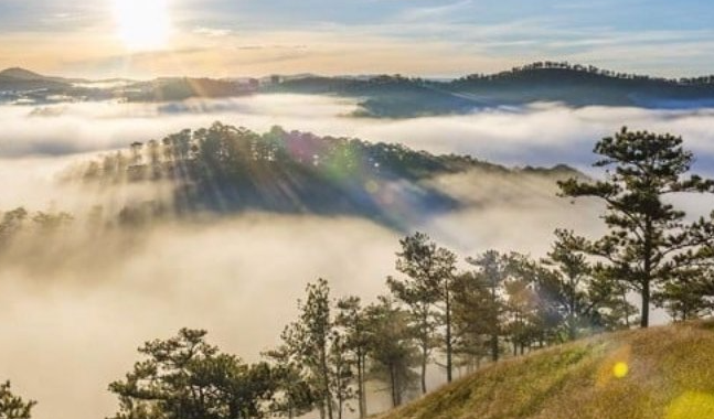 Cảnh bình minh rực rỡ trên đỉnh núi Langbiang, mây bồng bềnh bao quanh sườn núi.