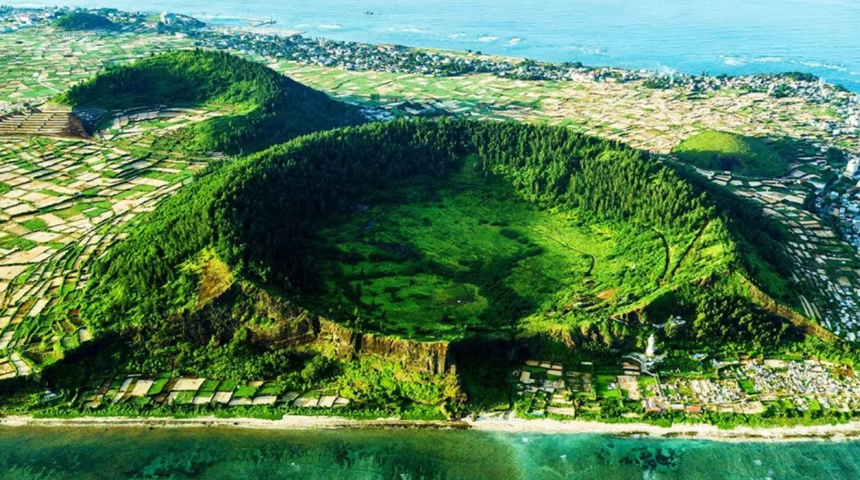 Toàn cảnh một ngọn núi lửa tĩnh lặng sau nhiều năm ngừng hoạt động, bao quanh là rừng xanh và hồ nước trong vắt.