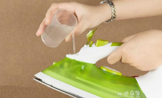 Người phụ nữ đang đổ nước cất vào bàn ủi hơi nước tại nhà.